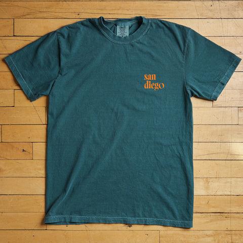 Teal t-shirt with 'San Diego' text on a wooden floor