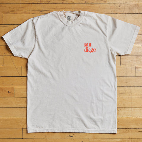 White t-shirt with 'san diego' printed in red on a wooden floor
