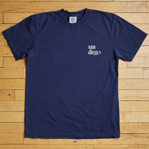 Navy blue t-shirt with 'san diego' text on a wooden floor