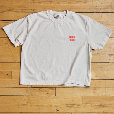 White t-shirt with red text on a wooden floor