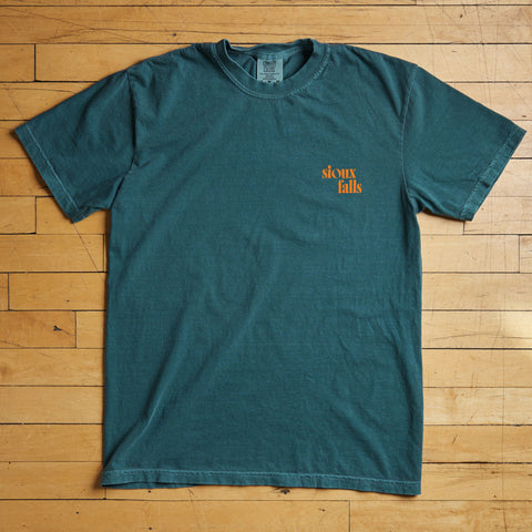 Teal t-shirt with a Sioux Falls logo on a wooden floor