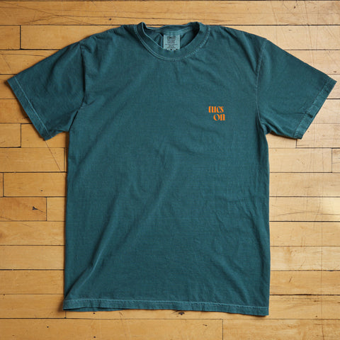 Green t-shirt with a tucson logo on a wooden floor