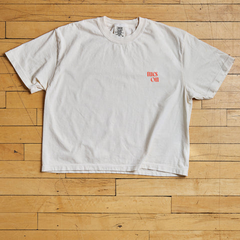 White t-shirt with red tucson text on a wooden floor