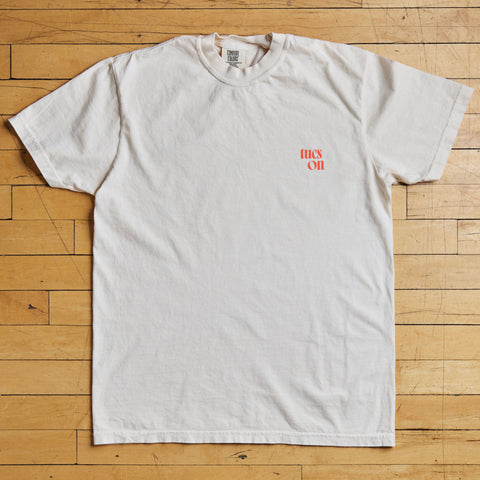 White t-shirt with red tucson text on a wooden floor