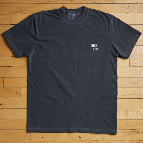 Black t-shirt with a tucson logo on a wooden floor