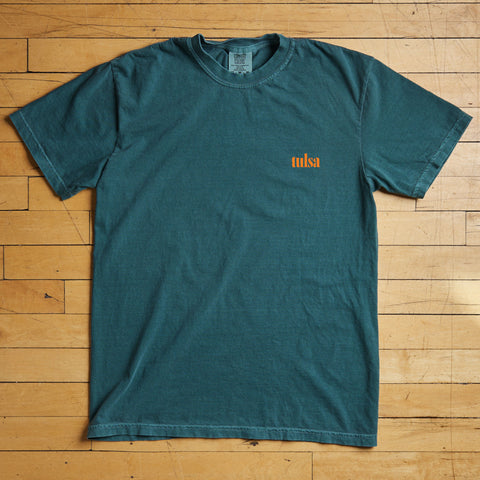 Teal t-shirt with 'tulsa' print on a wooden floor