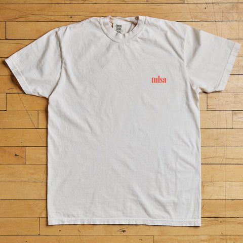 White t-shirt with red Tulsa text on a wooden floor