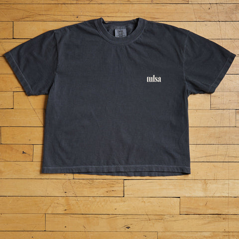 Black t-shirt with 'tulsa' logo on a wooden floor
