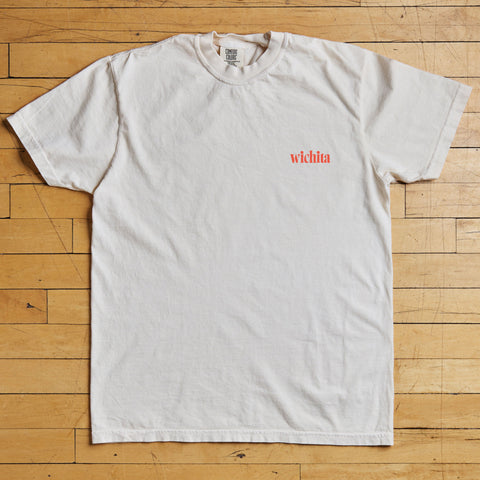 White t-shirt with red text on a wooden floor