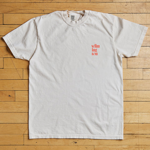 White t-shirt with red text on a wooden floor