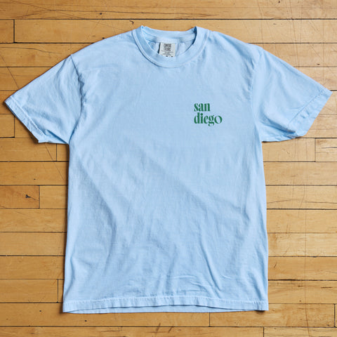 Light blue t-shirt with 'san diego' text on a wooden floor