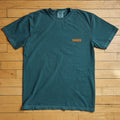 Green t-shirt with orange tampa logo on a wooden floor