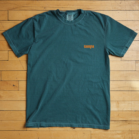Green t-shirt with orange tampa logo on a wooden floor