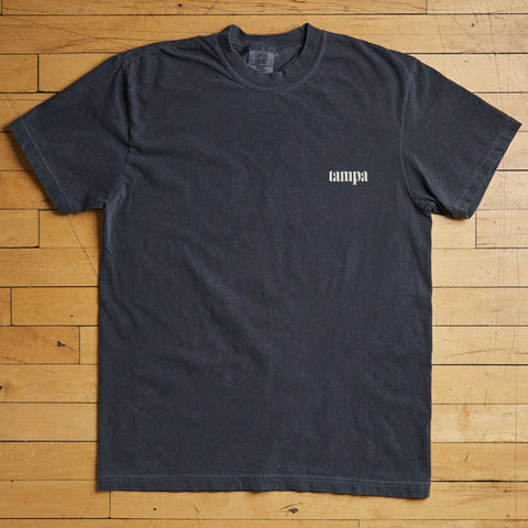 Black t-shirt with 'tampa' print on a wooden floor