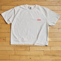 White t-shirt with a red Tulsa logo on a wooden floor
