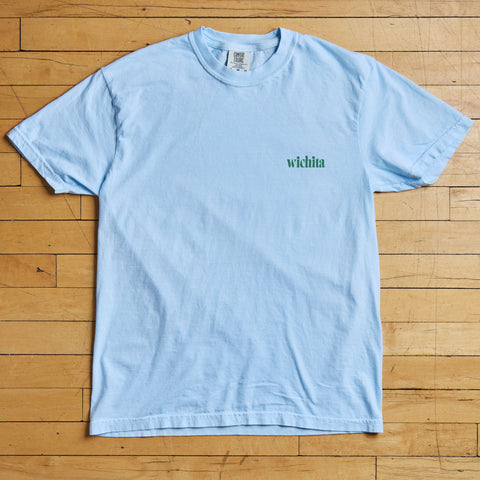 Light blue t-shirt with 'wichita' text on a wooden floor
