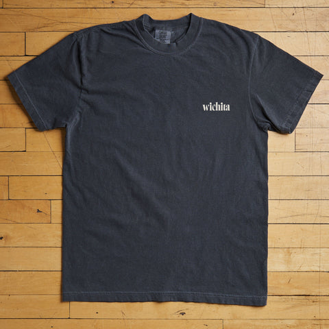 Black t-shirt with 'wichita' text on a wooden floor